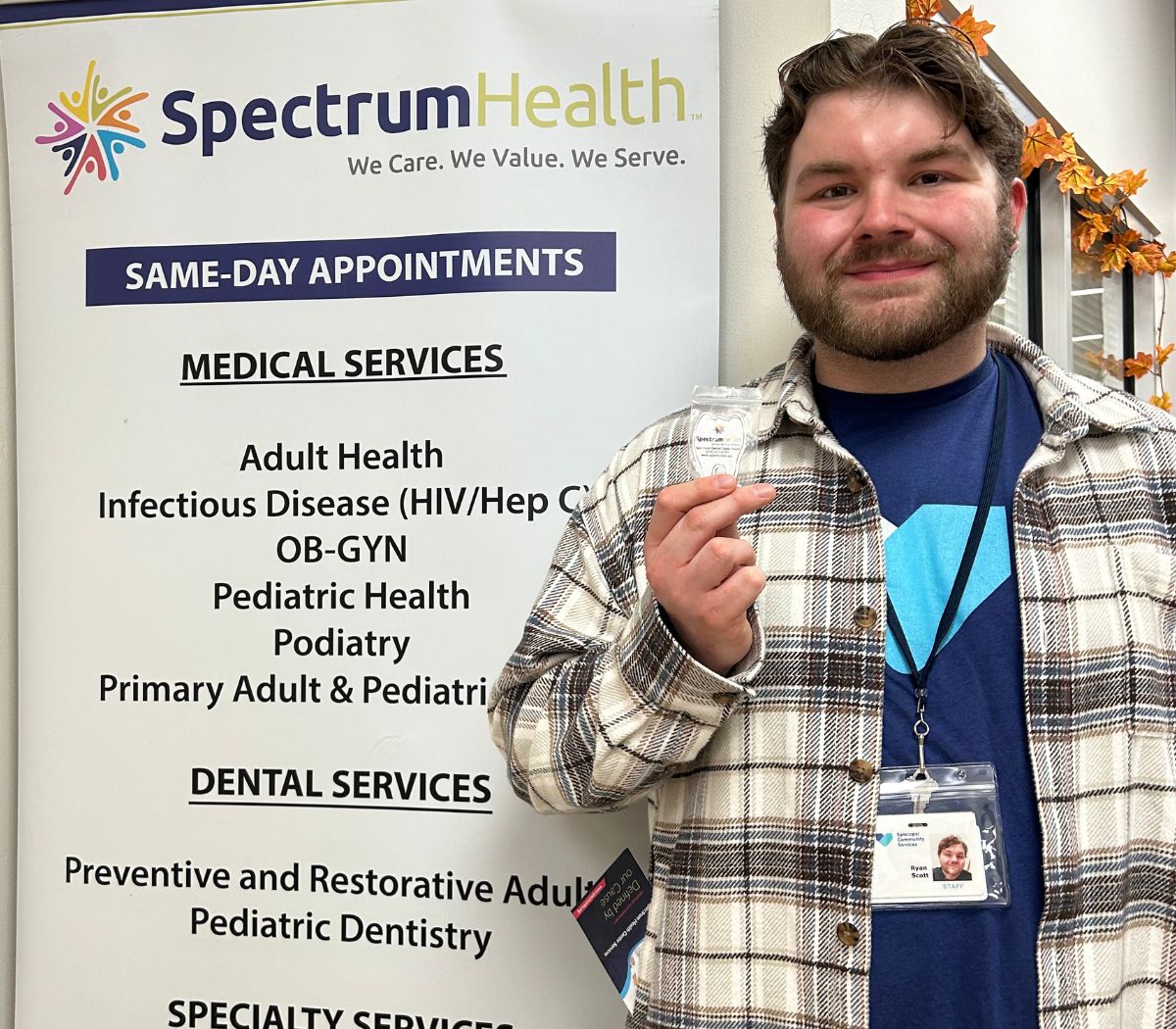 A Spectrum team member holds a sign listing Spectrum’s services at Fall Fest