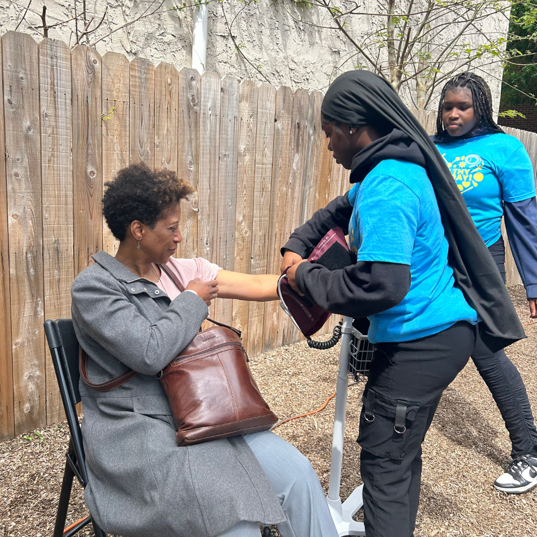 Staff in blue shirts help a woman seated outdoors