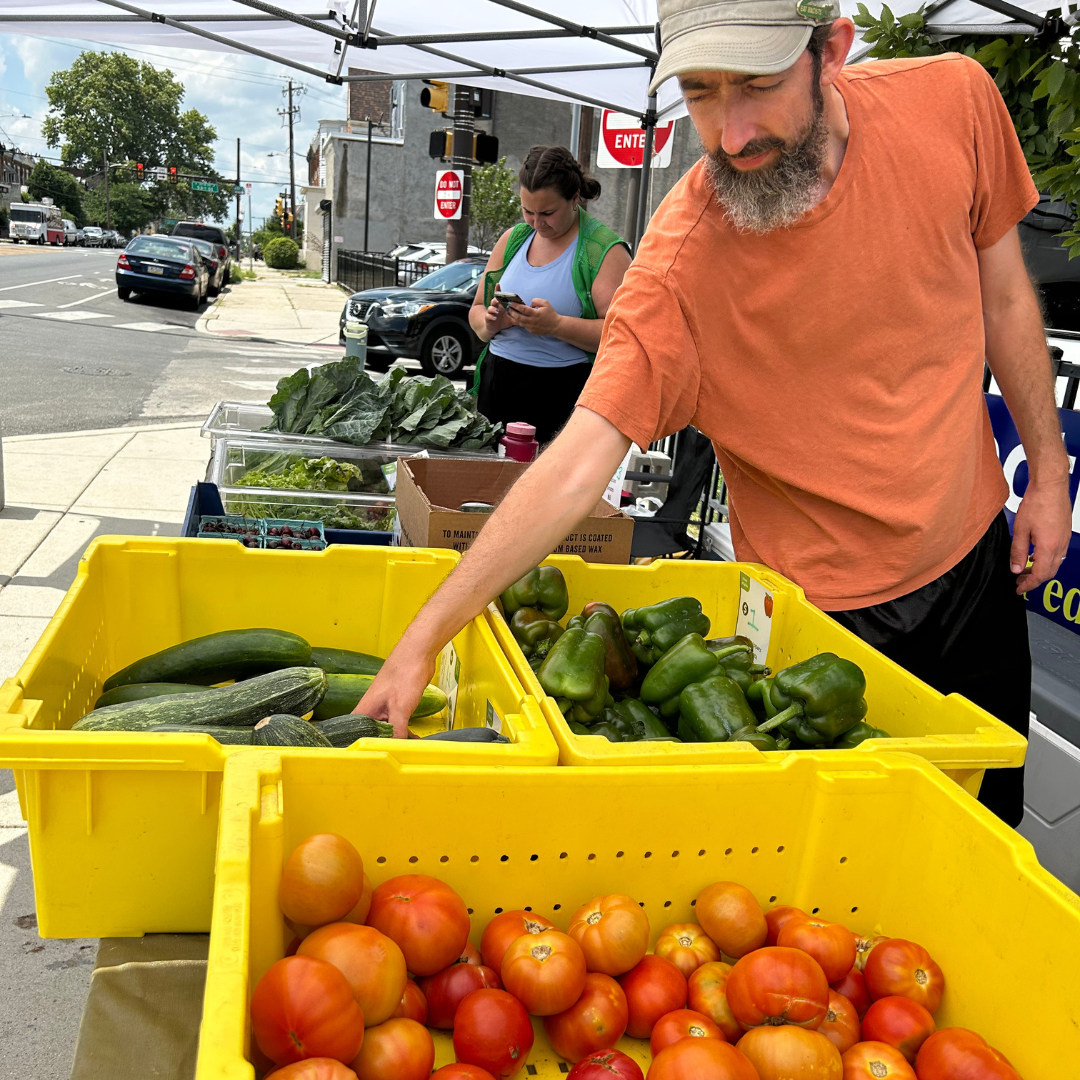 A man picks out fresh vegetables at a produce stand