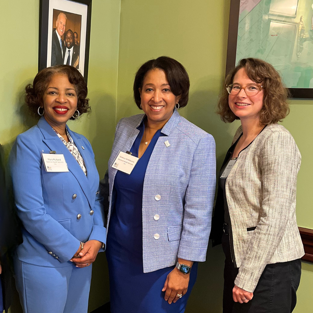 Three women stand together inside the Capitol