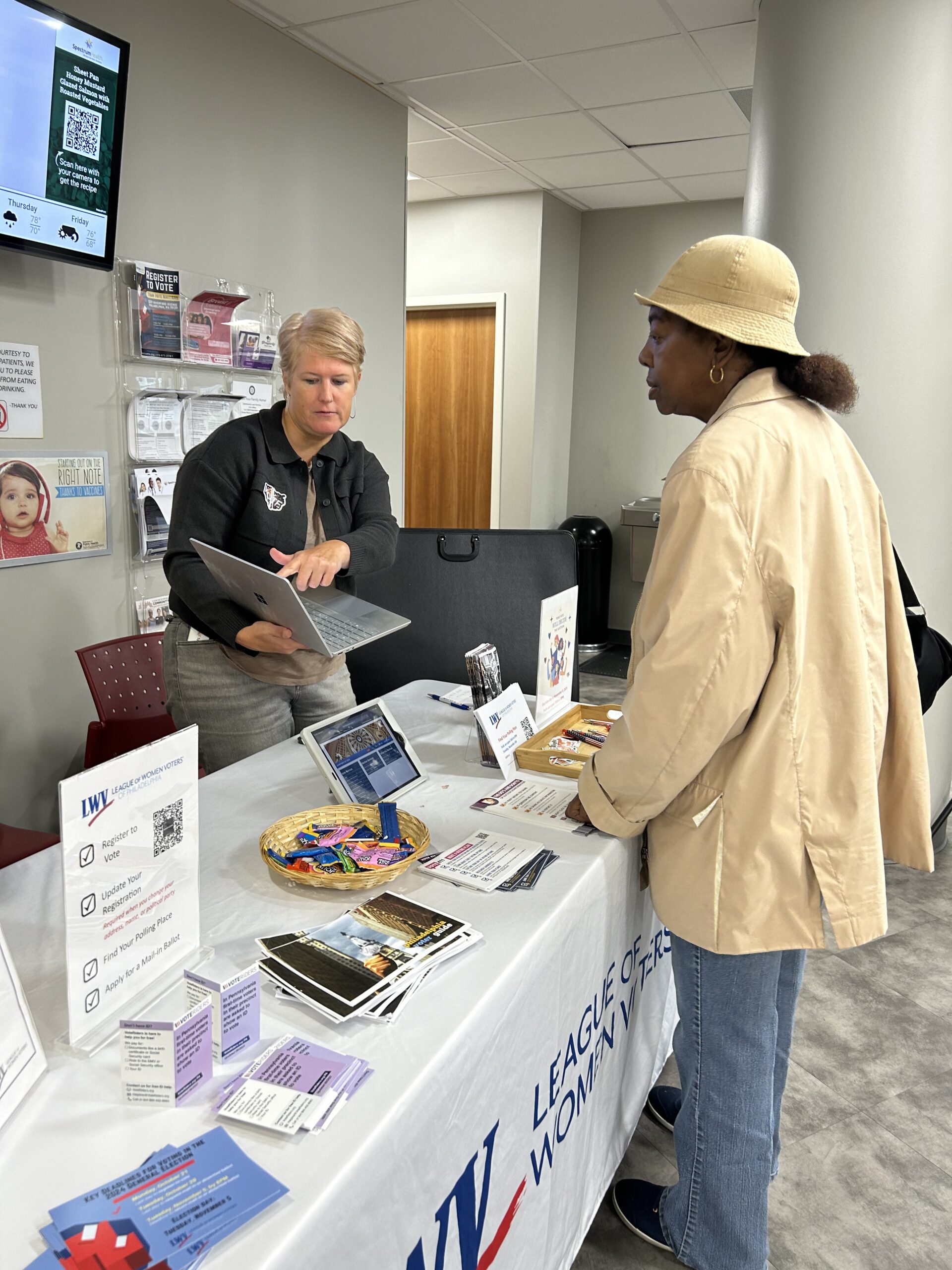 A staff member helps a guest at the voter registration table