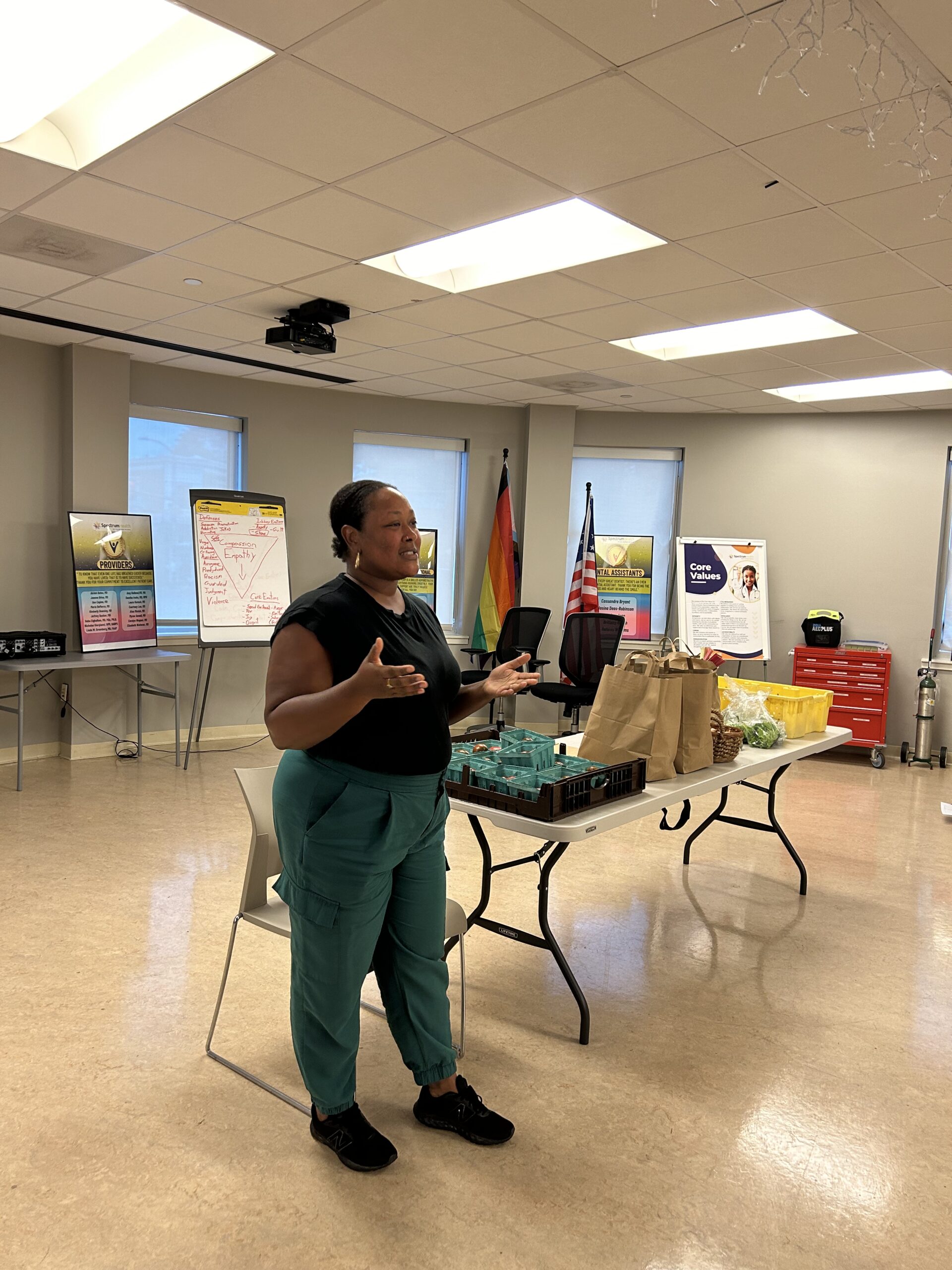 A presenter speaks next to a table of produce
