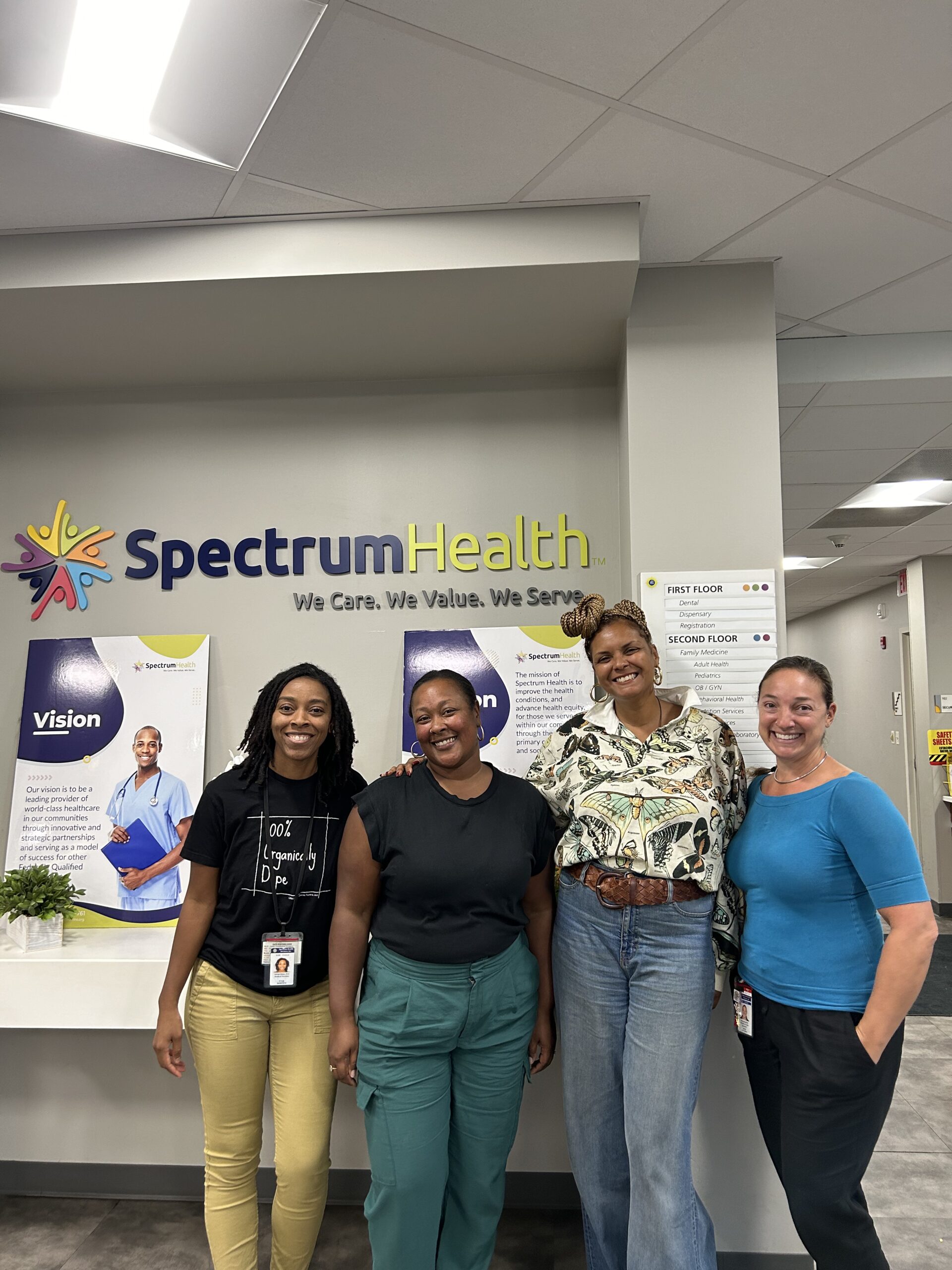 Four women stand in front of the Spectrum Health sign