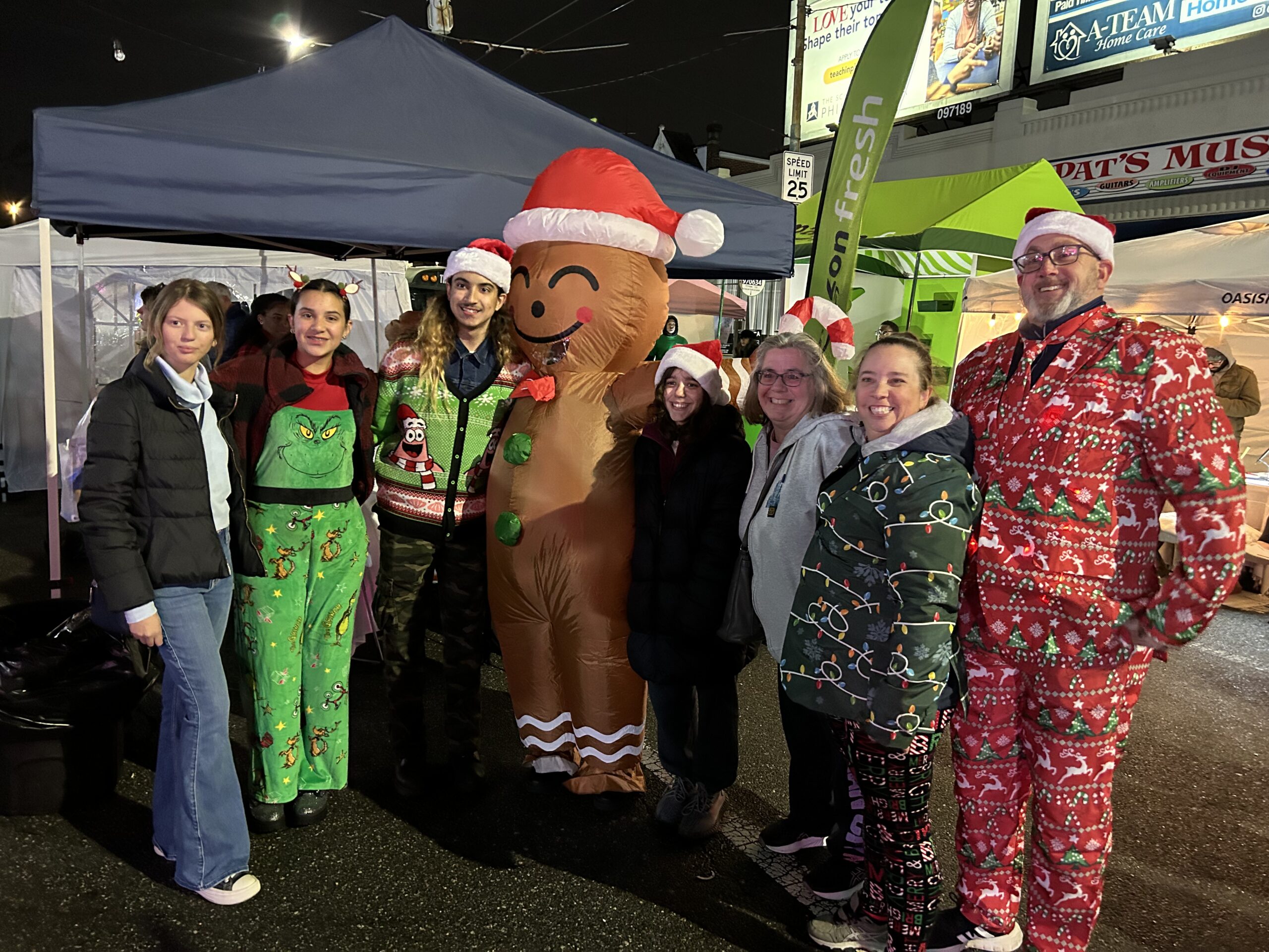 A group in holiday outfits poses with the gingerbread man