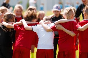 kids on a soccer team in a huddle with their arms around each other's shoulders