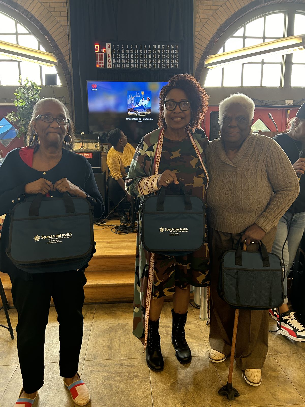 Three women hold Spectrum bags at the health fair