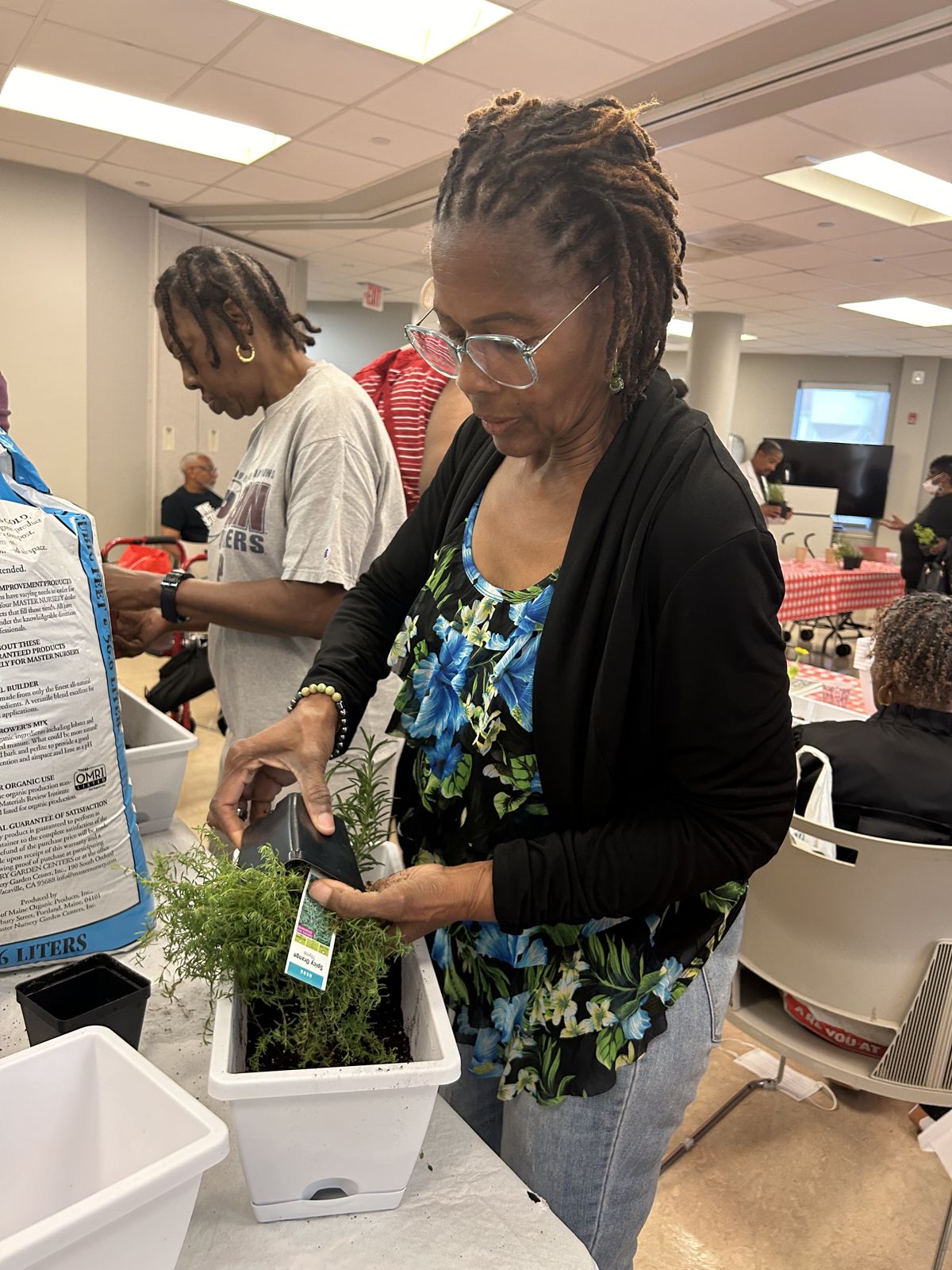 A guest pots a plant at the class