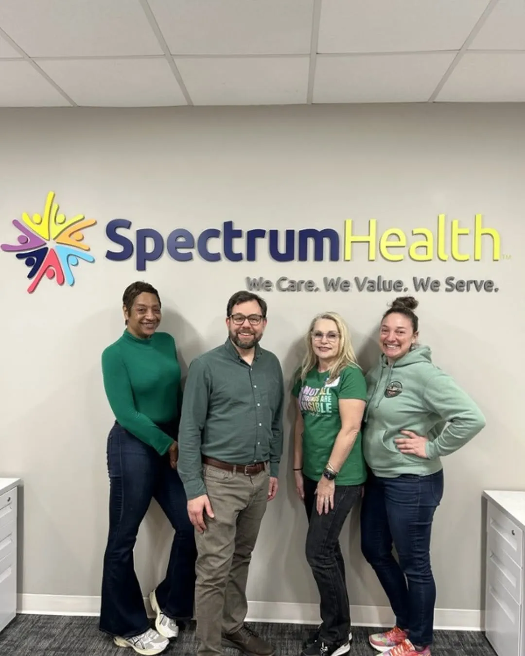 Four Behavioral Health team members wear green in front of the Spectrum Health sign.