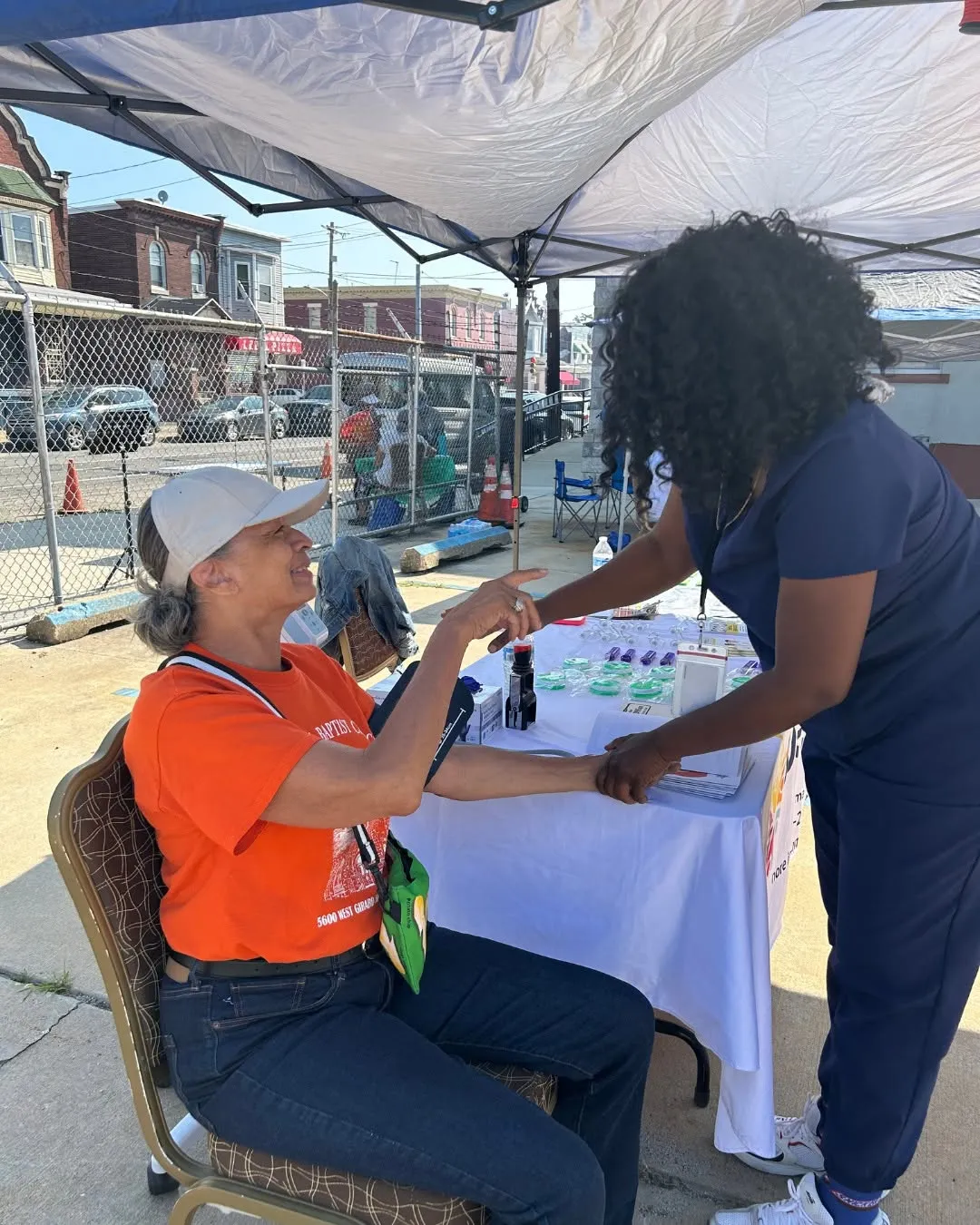 A nurse checks a woman’s blood pressure under a tent.