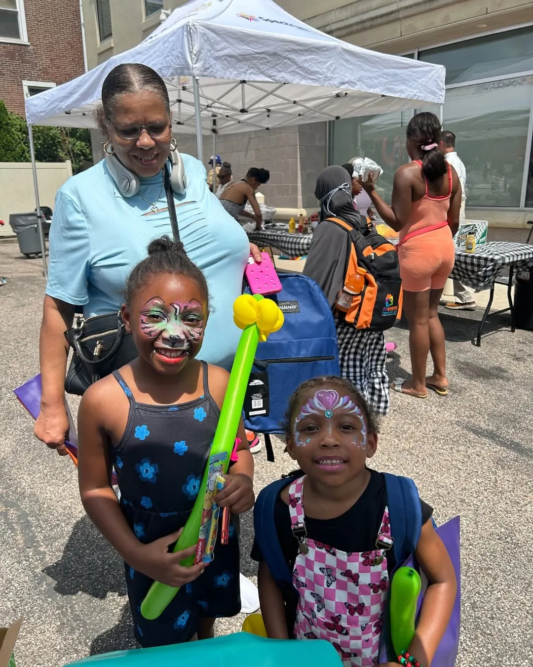 Two kids show off their face paint and balloon toys.
