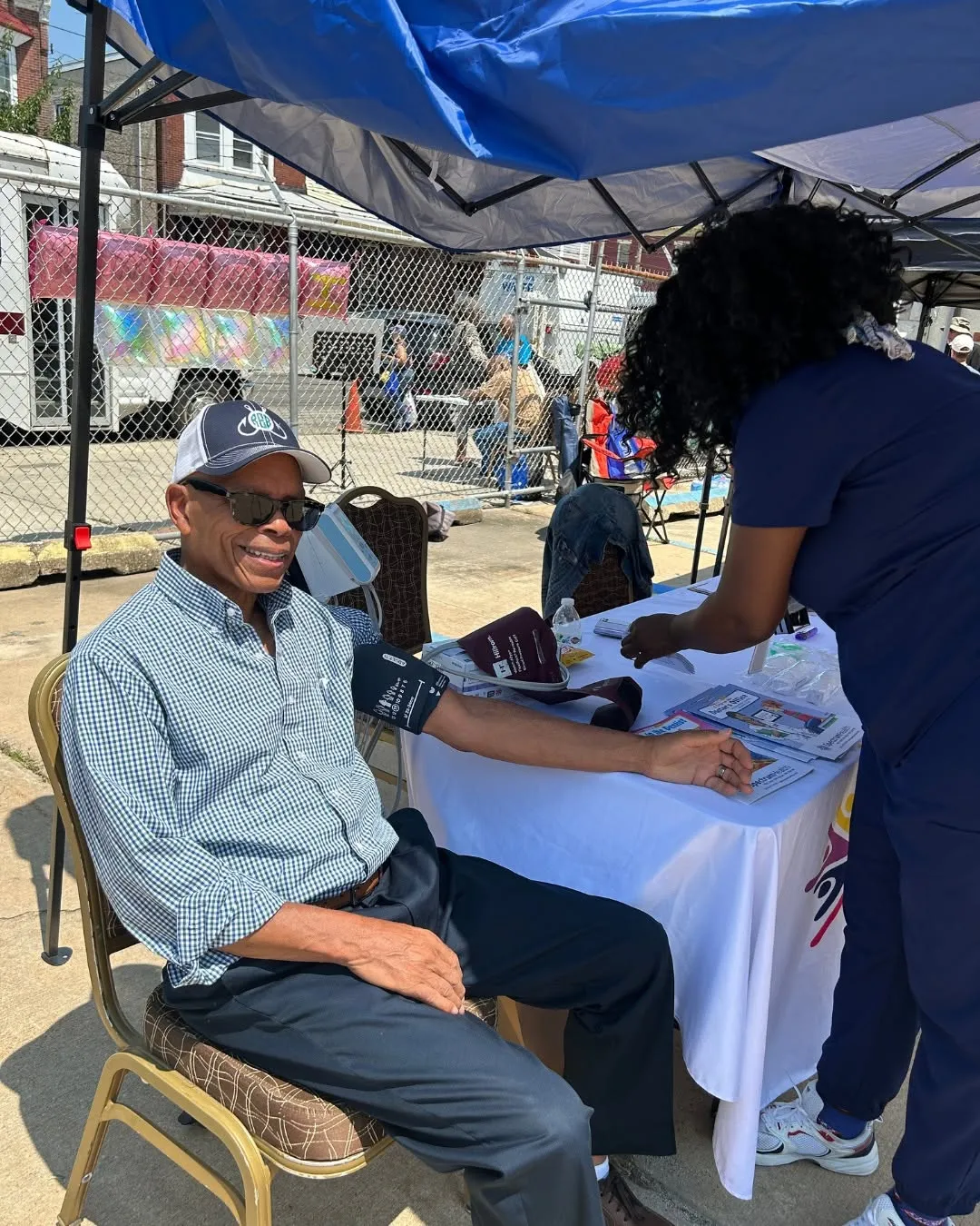 A man sits for a blood pressure check at the outdoor fair.