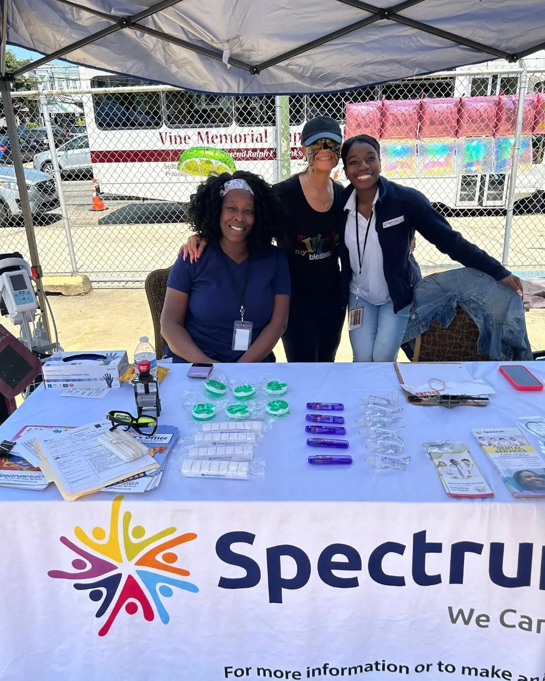 The Spectrum team smiles behind their table at the church community fair.