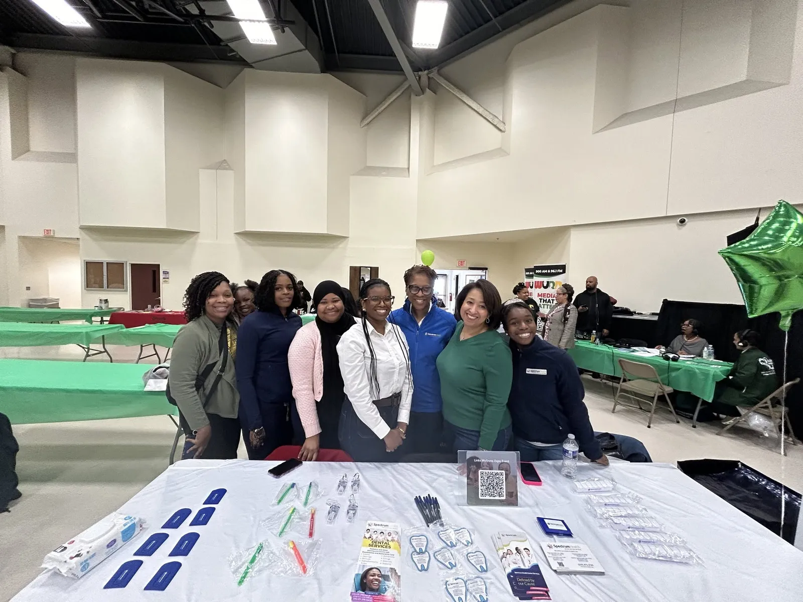 Spectrum Health team members stand together behind a table of health handouts at the wellness expo.