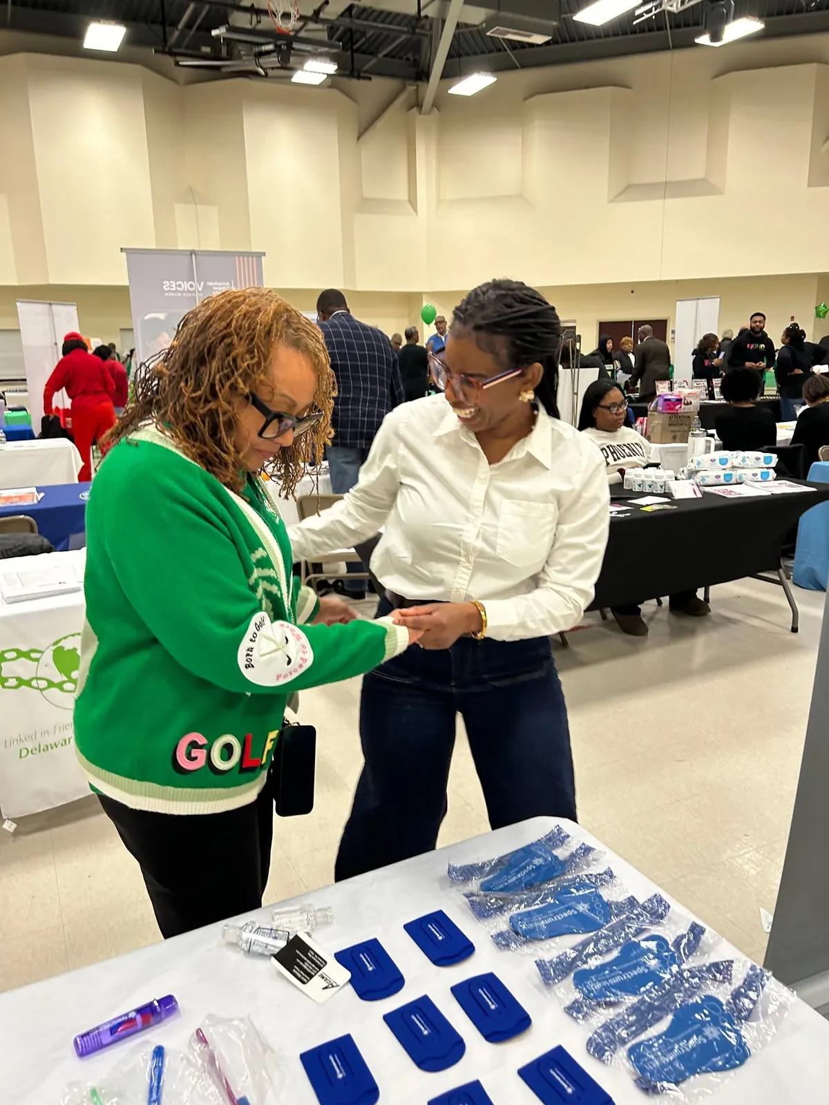A Spectrum staff member talks with a smiling visitor in a green sweater at the expo table.
