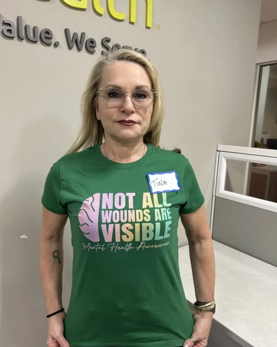 A staff member wears a green shirt that says Not All Wounds Are Visible.