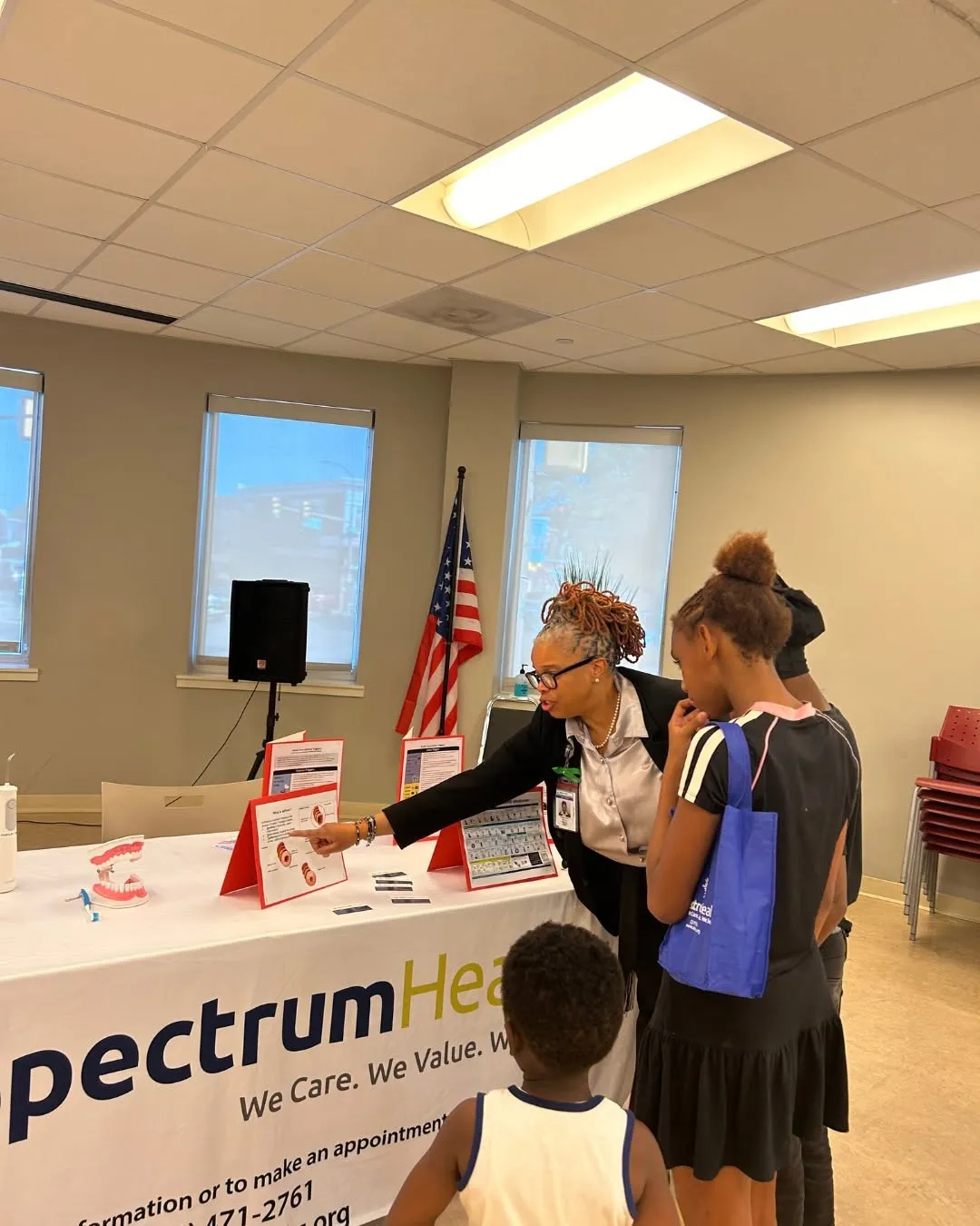 A Spectrum staff member shows information to teens at the welcome table.