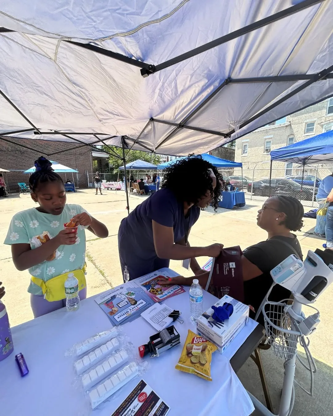 A young visitor stops by the health table while a nurse helps a guest.