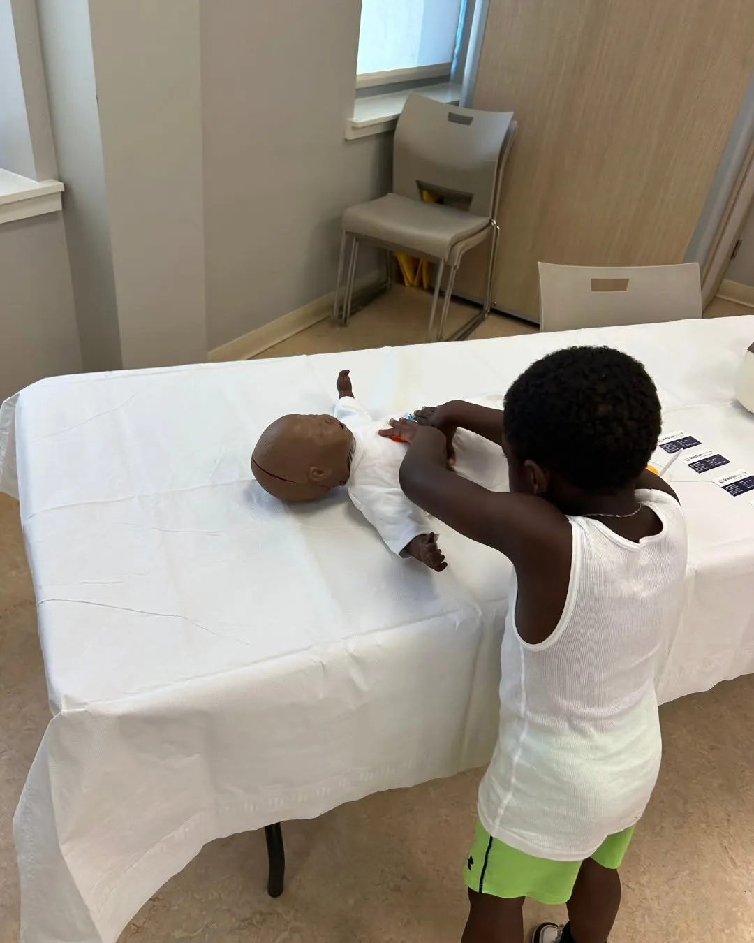 A young visitor practices on a baby CPR training doll.